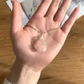 Detail van handgemaakte ketting met ruwe rozenkwarts kristal gewikkeld in zilverdraad - Hangerketting met omwikkelde ruwe steen (F83-2) / Rozenkwarts