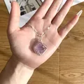 Close-up of handmade wire wrapped amethyst raw stone pendant on a delicate chain. - Light Amethyst