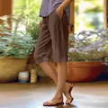 Detailed view of women's loose cotton linen shorts in brown with practical side pockets - S / Bottoms / Coffee