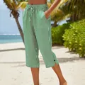 Close-up detail of green and white striped cropped pants with drawstring waist on a beach. - S / Bottoms / Green and White Striped