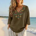Detail view of retro embroidered cotton linen V-neck blouse for women in a beach setting - Dark Khaki