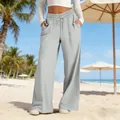 Detailed view of grey high-waisted wide-leg trousers for women on a beach setting - S / Bottoms / Light Gray