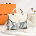 Elegante witte handtas met paisley-print en goudkleurige metalen handgreep getoond. - 23x11x18cm / Broken Wit
