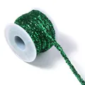 Close up detail of dark green sequin braided rope trim on white plastic spool craft supply - Christmas Green