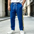 Blue men's sports trousers with yellow side stripes and white drawstrings in street setting - M / Bottoms / Blue
