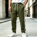 Close-up of olive green sweatpants featuring white side stripe and drawstring waist detail - M / Bottoms / Army Green