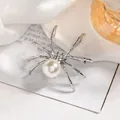 Macro view of a silver spider brooch featuring a large pearl and sparkling rhinestones - Silver