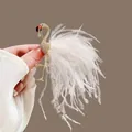 Macro detail view of an elegant gold flamingo brooch featuring soft white feathers - Flamingo-White Feather