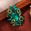 Vintage emerald green crystal rhinestone flower brooch with ornate gold-tone alloy base - Green