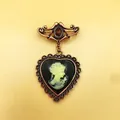 Détail d'une broche camée vintage en forme de cœur avec une pierre rouge et du métal cuivré. - Portrait de Camée Vintage