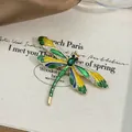 Close-up of elegant enamel dragonfly brooch featuring green crystals and rhinestones - Green Enamel Dragonfly