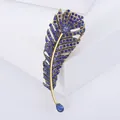 Detailed macro view of a vintage gold-tone feather brooch set with blue rhinestones - Blue