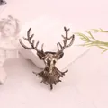 Close-up of a vintage bronze alloy deer head brooch with detailed antlers on a white base - Bronze