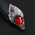 Detailopname van vintage bladvormige broche met grote rode druppelsteen en tinnen finish. - Bladvorm met Rode Druppelsteen