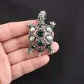 Vista dettagliata di una spilla a tartaruga vintage con cristalli verdi e iridescenti. - Argento Antico + Verde Scuro