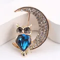 Eleganter goldfarbener Eulen-Brosche auf Mondsichel mit großem facettiertem blauen Kristall - Eule Mit Mond Großer Blauer Stein (E3-6-8981)