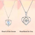 Twee zilveren hartvormige hangers met bewegende steen en unieke iriserende edelsteen. - Geschenkdoos / Oceaan Hart en Hartslag Witte Set
