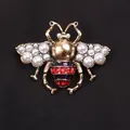 Vintage gouden bijenbroche met parels en rode strasstenen op zwarte stoffen achtergrond - Parel Vleugel Vintage Bij Stijl (K2-5-2276)