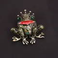Vintage groene kikkerspeld met gouden kroon en rode lippen op zwarte achtergrondstof. - Groene Emaille Kikker Met Kroon (J4-6-1083)