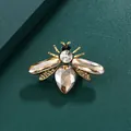 Elegante gouden bijenbroche met champagne kristallen op groene getextureerde achtergrond - Drie Champagne Kristal Grote Bij Stijl (J5-1-1100)
