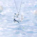 Elegante zilveren dolfijn hanger ketting met parel en fonkelende stenen op water achtergrond - Eenvoudige Verpakking / Walvisval