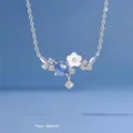 Gedetailleerd overzicht van zilveren bloemenketting met blauw kristal en witte bladen - Eeuwige Bloem / Eenvoudige Verpakking