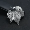 Gedetailleerde close-up van een vintage bladbroche met antieke zilveren afwerking - Esdoornbladvorm met Grijze Parel