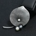 Detailopname van een retro broche met antieke tinnen afwerking en parels. - Bladvorm met Drie Parels
