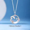 Close-up of a silver snake-shaped necklace pendant with pink crystals and moon inlay - Snake on Moon