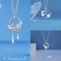 Detailansicht von drei silbernen Halsketten mit blauen Edelsteinen und Blumenmotiven - 3-teiliges Set - Quaste + Herz + Emaille