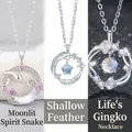Detailed view of three elegant necklaces featuring snake, feather and ginkgo leaf designs. - Snake Moon + Feather + Ginkgo Style