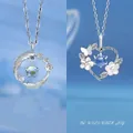 Elegante silberfarbene Feder- und Blumenherz-Halsketten auf blauem Hintergrundverlauf. - Feder und Herz Blumen Stil / 2 Stück/Set