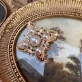 Macro detail of vintage baroque brooch with pearls and crystals in gold frame art - Pink Pearl Rhinestone Cross Style