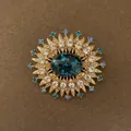 Close-up of vintage gold sunburst brooch with blue central stone and sparkling rhinestones. - Sunburst Flower Shape (Style 4)
