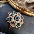 Vintage baroque gold brooch with multicolored crystals on a dark stone surface. - Hollow Multi-Color Crystal Palace Style