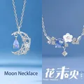 Elegante zilverkleurige kettingen met maan- en bloemenhangers en blauwe stenen. - Floating water moon + flower wei young / Geschenkdoos