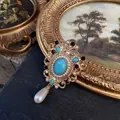 Elegant Baroque style gold brooch featuring a turquoise center stone, pearls and crystals - Sky Blue Turquoise & Purple Crystal Style