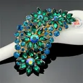 Close-up of elegant floral brooch with green and blue crystals on a dark background - Gold Green