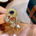 Elegant vintage sunflower brooch detail featuring a blue gemstone center and a grey pearl. - Sunflower Design (H9-6-2917)