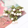 Elegant vintage green cranberry brooch featuring metallic leaves and dangling white pearls - White