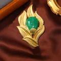 Close-up of a vintage golden leaf brooch featuring a polished green central stone. - Brushed Gold Leaf Emerald Style (6)