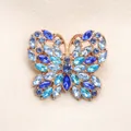 Elegante broche de mariposa con pedrería azul en una montura clásica bañada en oro. - Azul