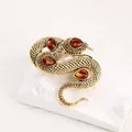 Gedetailleerd overzicht van een vintage gouden slangenbroche met amberkleurige edelstenen - Stijl 13 (Amber Stenen)