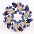 Elegante bloemenkrans broche met fonkelende blauwe strasstenen en gouden bladeren voor pakken - Blauw