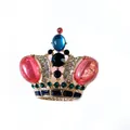 Close-up macro view of vintage crown brooch with colorful gemstones and rhinestone inlay - Red