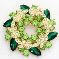 Elegante goudkleurige kransbroche met sprankelende groene en witte strassteentjes - Groen