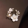 Elegante bloemenkrans broche met witte schelpenbloemen en een centrale parel accent - Stijl 11