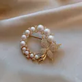 Elegante goudkleurige kransbroche met witte parels en een fonkelende vlinder voor pakken - Stijl 12