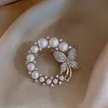 Elegante zilveren kransbroche met witte parels en een fonkelende vlinder van strass. - Stijl 13