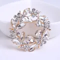 Elegante gouden kransbroche met fonkelende heldere kristallen in een bloemmotief. - Stijl 22
